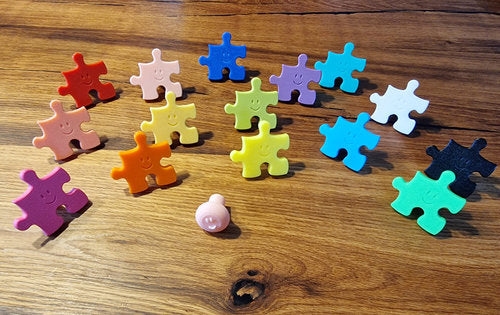 Bunte Kinderzimmer Wandhaken in Puzzle-Form auf einem Holztisch, ideal für die Aufbewahrung im Kinderzimmer.
