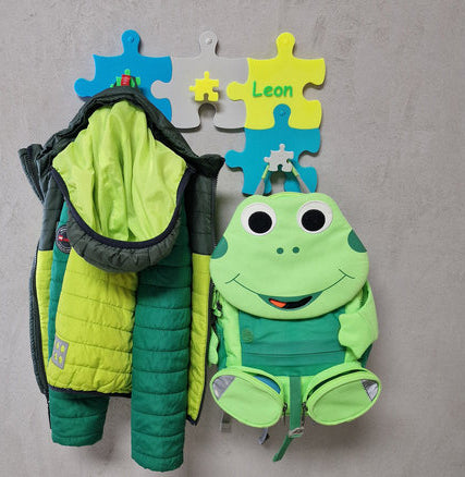 Kinderzimmer Garderoben-Erweiterung mit bunten Haken, grüner Jacke und Frosch-Rucksack von Leon.