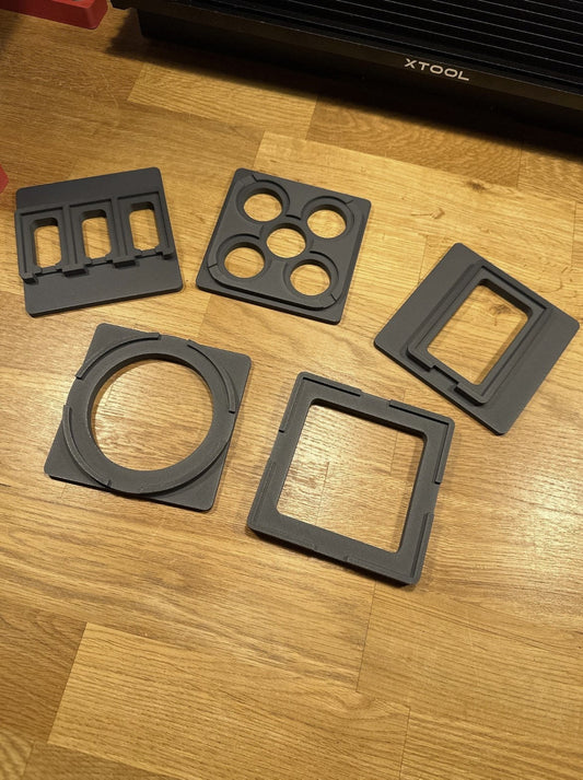 Xtool F1 Jigs – fünf verschiedene Jigs für präzise Bauteilaufnahmen auf einem Holzuntergrund.