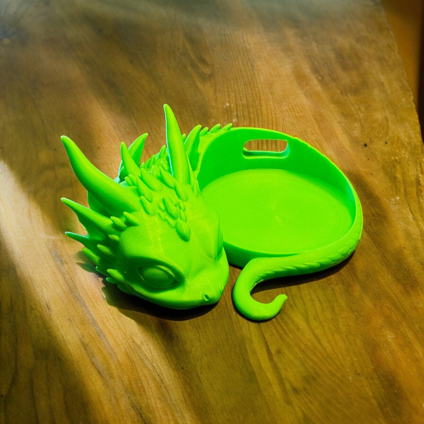Drachenbaby Halter Alexa Echo Dot – Verspielter Baby Drache in leuchtendem Grün auf Holztisch.
