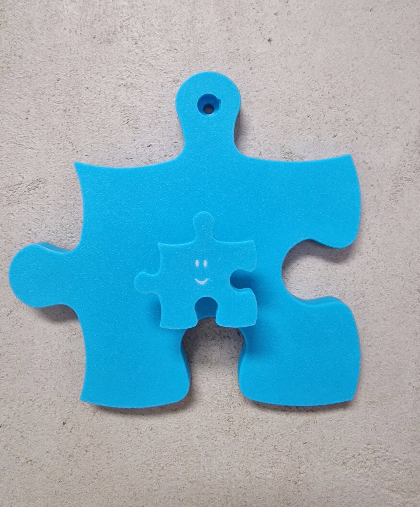 Kindergarderobe Puzzle – blauer Garderobenhaken in Puzzleform mit kleinerem Anhänger.