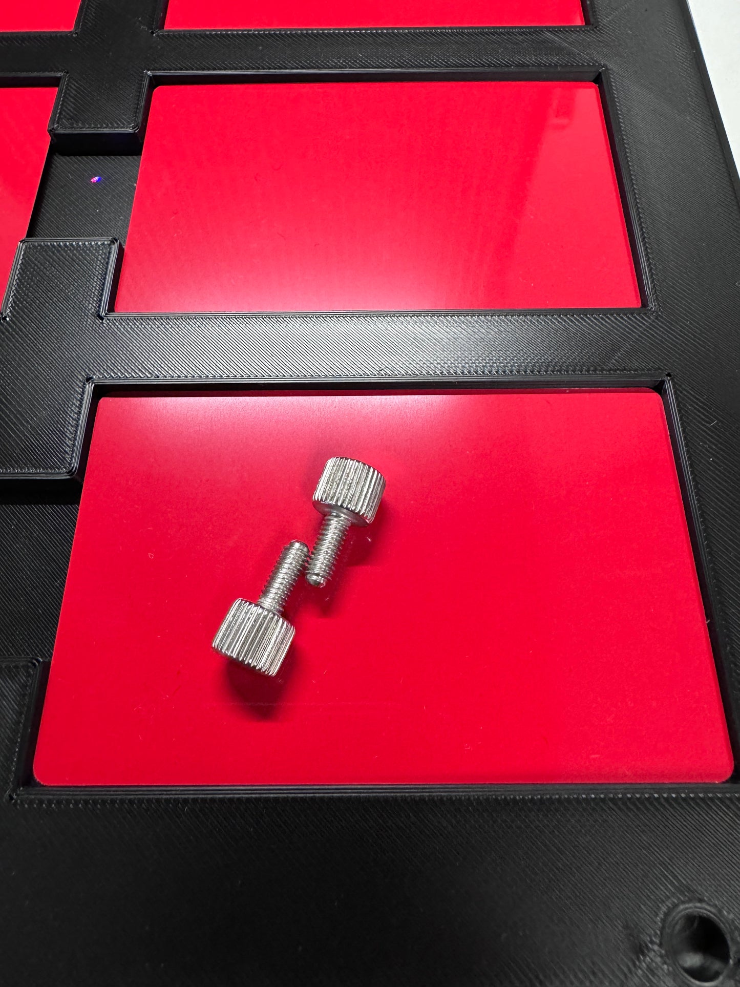 xTool F1 Ultra Business Card Jig with silver screws on red surface for precise engraving.