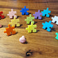 Bunte Kinderzimmer Wandhaken in Puzzle-Form auf einem Holztisch, ideal für die Aufbewahrung im Kinderzimmer.
