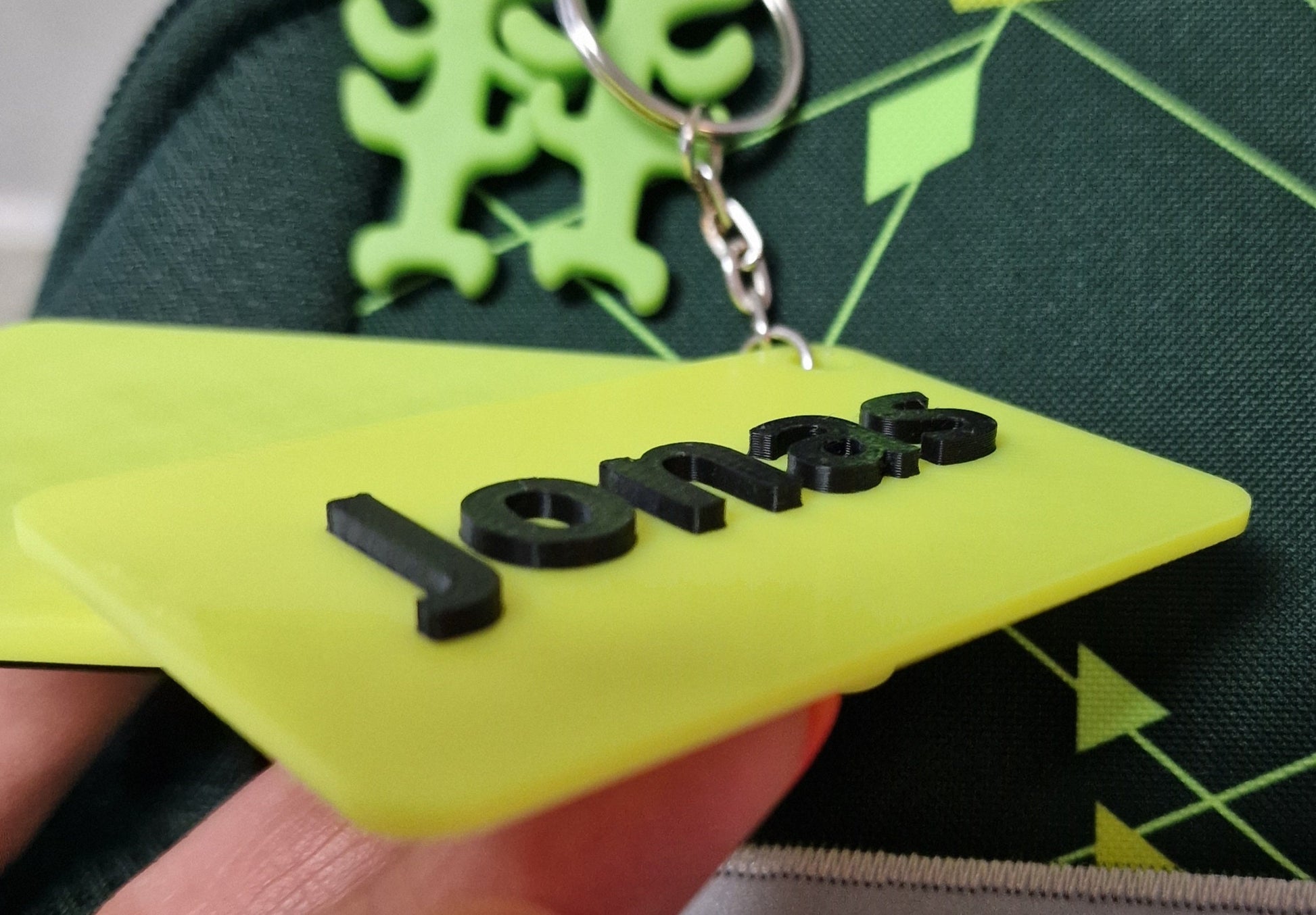 Personalisierter Anhänger mit Namen in leuchtendem Gelb und schwarzer Lasergrafur für Schulranzen.