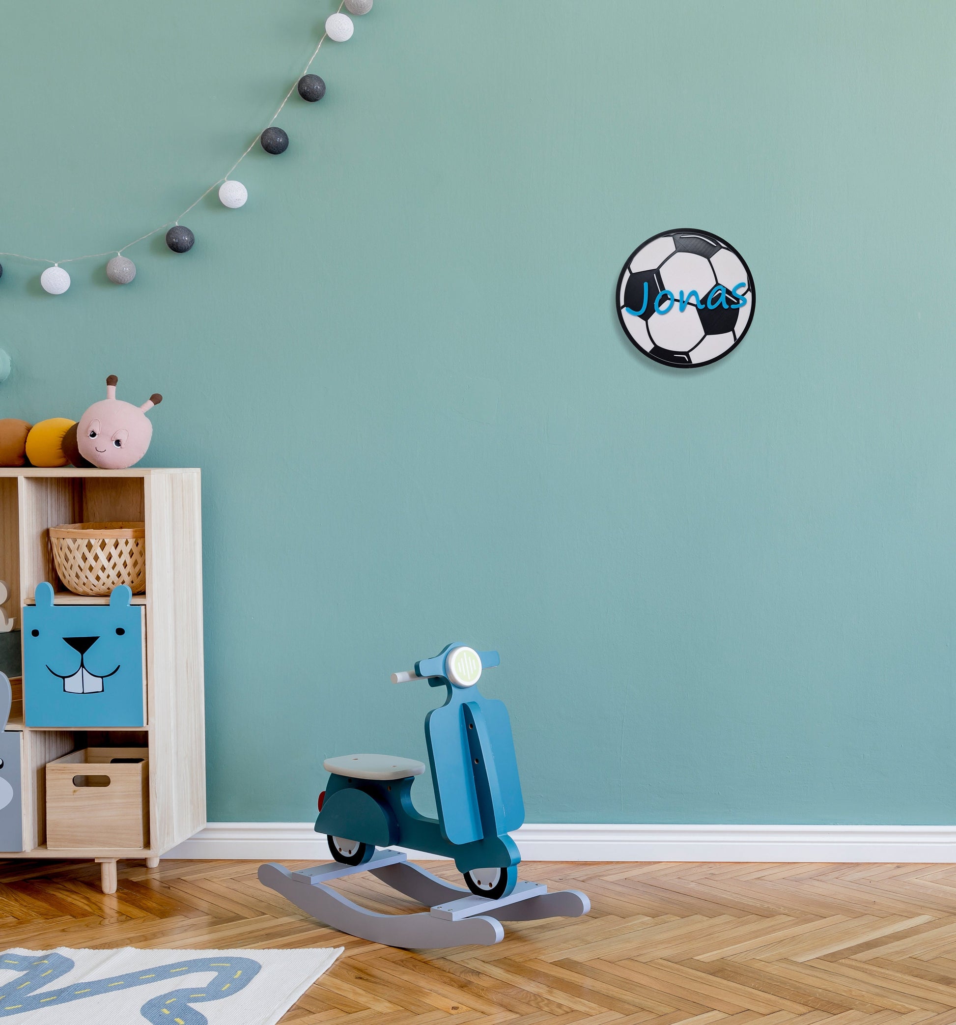 Personalisierbares Fußball-Türschild mit dem Namen Jonas im Kinderzimmer mit blauen Wänden und Spielzeug