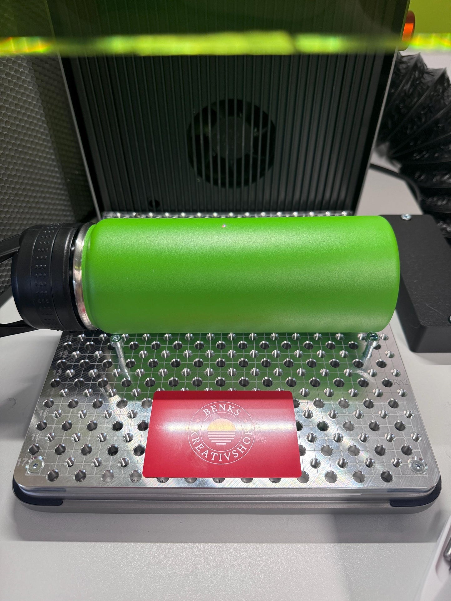 xTool F2 Ultra Jigmaker displaying a green thermos on a fixture plate with a branded logo.