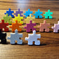 Kindergarderobe Puzzle – Bunte, personalisierbare Puzzle-Haken für Kinderzimmer, mit lächelnden Gesichtern.