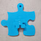 Kindergarderobe Puzzle – blauer Garderobenhaken in Puzzleform mit kleinerem Anhänger.